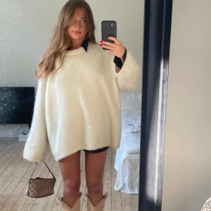 Oversized vit stickad tröja k mohair - Säljer en oversized beige stickad tröja med rund halsringning och långa ärmar. Tröjan har en mjuk och fluffig känsla, perfekt för lager-på-lager. Tröjan är från H&M och är i en mohair- och ullblandning. 