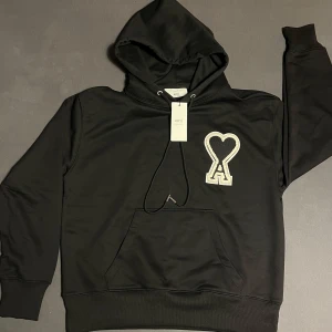 AMI Paris  hoodie  - Säljer denna fina svarta Ami hoodien som är nästan oanvänd. Jag köpte den när jag va i Tyskland. Men använde den bara 3 gånger men kände att den inte passa mig. Har du funderingar kan du bara ställa de. Priset diskuteras vid snabb och smidig affär 