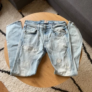 Ljusblå slitna Replay jeans - Hallå hallå👋 Säljer ett par ljusblå jeans från Replay med slitningar och lagade detaljer på benen i Anbass modell👖  Klassisk femficksmodell med normal passform och dragkedja. Perfekta för en avslappnad och enkel stil😮‍💨  Storleken är W32 L32📏  Priset kan diskuteras vid snabb affär!💸  Vid frågor: Meddela📩