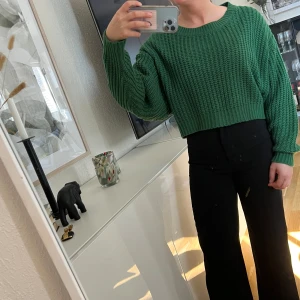 Grön croppad stickad tröja från SHEIN - Säljer en grön croppad stickad tröja från SHEIN. Tröjan har en lös passform, bred rund halsringning och långa ärmar. Perfekt för lager-på-lager och enkel att styla till olika outfits.