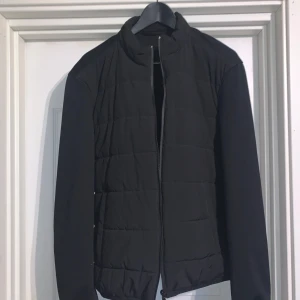 Svart quiltad jacka från Zara - Säljer en svart quiltad jacka från Zara med dragkedja framtill. Jackan har en stilren design med ståkrage och långa ärmar. Perfekt för dig som vill ha en enkel och snygg jacka till vardags.