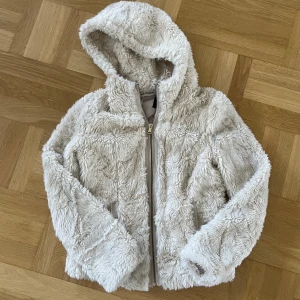 Pimkie jacka - Mysig beige jacka från Pimkie med huva o dragkedja framtill🥰 jackan är fluffig med långa ärmar, ingen storlek men uppskattar xxs-xs. Enda defekt är en rivning som enkelt sys ihop o inte syns från utsidan alls (se bild 4) därav pris