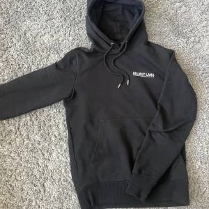 Svart hoodie från Helmut Lang - Säljer en svart hoodie från Helmut Lang med broderad logga på bröstet. Tröjan är väldigt bra skick och byten är intressant!!🙏🙏🙏