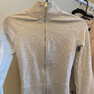 Ljusgrå ziptröja från Nelly - Säljer min ljusgrå zipup/yoga jacket från Nelly som är i fint skick utan defekter. Formar sig fint efter kroppen och är jättefin tröja!! Säljer för att jag inte längre har användning av den då jag köpt en lululemon nyligen🥰