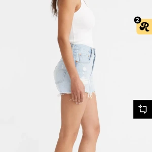 Levi's 501 Original Shorts i ljusblå denim - Klassiska Levi's 501 shorts i ljusblå denim med fransade benslut och femficksmodell. Hög midja och knappgylf. Perfekta för sommaren och har den ikoniska Levi's-lappen bak. W26