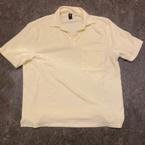 Gul kortärmad tröja från SOC - Säljer en ljusgul t-shirt från SOC i storlek S. T-shirten har krage, korta ärmar och en bröstficka. Perfekt för en avslappnad stil och enkel att matcha med jeans eller shorts under en solig dag i sommaren.