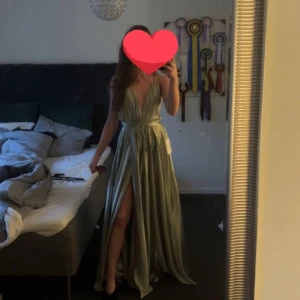 Ljusgrön långklänning med slits och v-ringning - Säljer en elegant ljusgrön långklänning med djup v-ringning och hög slits framtill. Klänningen har omlottkänsla i midjan och är ärmlös, perfekt för bal eller fest. Snyggt fallande material som ger en lyxig känsla. Använd endast 1 gång, kan tänka mig ändra pris!❤️