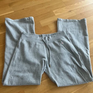 Grå mjukisbyxor från Champion - Grå mjukisbyxor från Champion med dragsko i midjan och rakt, lite vidare ben. Byxorna har en liten broderad Champion-logga framtill och är tillverkade i mjuk bomullsmix. Perfekta för en avslappnad stil.