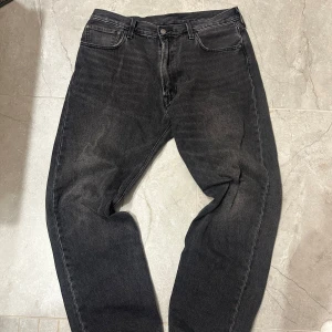 Svarta Levis 551 jeans W36 L32 - Säljer ett par svarta Levis 551 jeans i storlek W36 L32. Klassisk femficksmodell med raka ben och normal passform. Jeansen har en snygg tvättad look och är perfekta för en avslappnad stil.