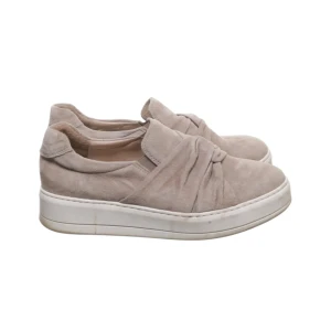 Sneakers - Säljer ett par snygga beige slip-on sneakers med en unik knutdetalj framtill. Skorna har en tjock vit platt sula och är tillverkade i mjuk mocka.