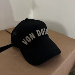 Von Dutch keps  - Svart Von Dutch trucker keps med ett cleant beige tryck i speciellt nice material. 