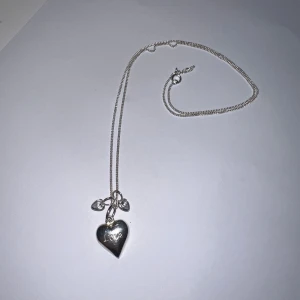 Halsband med hjärthänge från Edblad - Snyggt silverfärgat halsband från Edblad med ett hjärthänge där det står 'Love' ingraverat. Kedjan är tunn och smidig, och hänget har även små detaljer i form av två mindre berlocker. Perfekt accessoar för att lyfta din stil. Pris går att diskuteras☺️