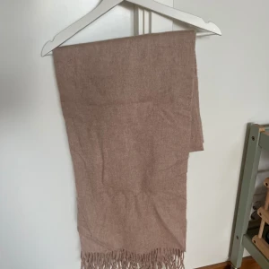 Halsduk WERA - Beige/ljusrosa stor halsduk från WERA i 100% ull. Väldigt mjuk och skön. I mycket bra skick, endast använd ett fåtal gånger.
