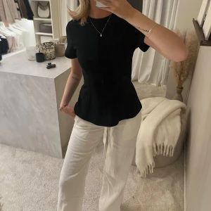 Svart figursydd topp från H&M  - Säljer en svart figursydd blus med korta ärmar och rund halsringning. Blusen har en stilren och enkel design som passar perfekt till många olika outfits. Materialet känns mjukt och bekvämt mot huden. Helt slutsåld på H&M 🤎🤎