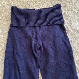 Mörkblå stickade byxor från Nelly - Mörkblå stickade byxor från Nelly med bred ribbad midja. Byxorna är mjuka och har en relaxed passform, perfekta för en chill look. Materialet är stickat och ger en mysig känsla. Byxorna går att vika ner i midjan och benen i bra längd