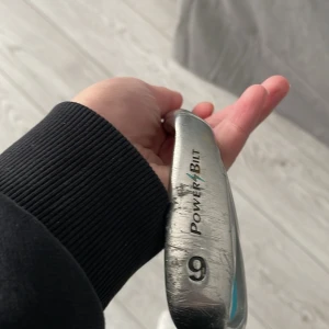 Golfklubba PowerBilt Momentum 9 järn - Säljer en PowerBilt Momentum 9 järn golfklubba i silver med blå detaljer. Klubban har svart grepp och är tillverkad i metall. Perfekt för dig som vill komplettera din golfutrustning med ett järnklubba.