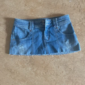Blå jeanskjol från Perin Extra - Säljer en blå jeanskjol från Perin Extra i klassisk denim med slitna detaljer och rå kant nertill. Säljer för att den är lite för kort