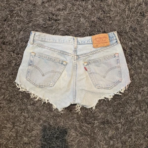 Ljusblå jeansshorts från Levi's - Ljusblå jeansshorts från Levi's med fransig kant och klassisk femficksdesign. Köpta second hand och därav mindre skavanker(se bild) men utöver det i fint skick. 