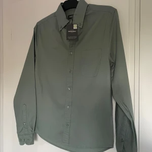 Oanvänd grön Dressmann skjorta  - Snygg grön oxfordskjorta från Dressmann i slim fit-modell. Perfekt för sommaren. Stl S. Oanvänd. 