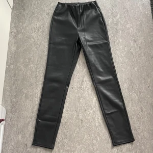 Svarta skinnleggings med hög midja - Snygga svarta leggings i skinnimitation med hög midja och tight passform. Aldrig använda😊