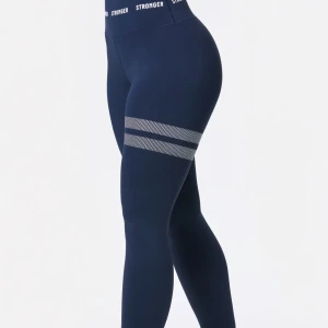 Mörkblå Stronger tights - Supersnygga mörkblå träningsbyxor från Stronger med hög midja och vita loggor i midjebandet. De har två vita randiga detaljer på låret och är tillverkade i ett stretchigt syntetmaterial som passar perfekt till träning. Storleken är S men passar även en Xs. Byxorna är använda få gånger och nyrpiset är 700kr💕