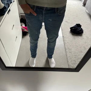 Blå tapered jeans Jack&Jones - Säljer ett par blå jeans med tapered passform från Jack&Jones. Jeansen har slitna detaljer och klassisk femficksdesign. De är i normal midja och har en smalare passform nedtill. Perfekta för dig som gillar en avslappnad men ändå snygg stil.