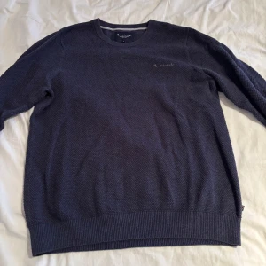 Mörkblå stickad tröja Bondelid L - Säljer en mörkblå stickad tröja från Bondelid i storlek L. Tröjan har rund halsringning, diskret broderad logga på bröstet och ribbade muddar vid ärmslut och nederkant. Perfekt för lager-på-lager under kyliga dagar.