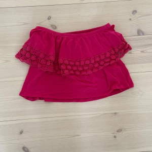 Rosa offshoulder tubtopp från Gina Tricot - Superfin rosa offshoulder tubtopp från Gina Tricot med volang och broderade blommor längs kanten. Perfekt för varma dagar och ger en riktigt söt vibe. Mjuk och skön, lätt att matcha med både jeans och kjol.