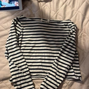 Randig långärmad tröja i bomull - Snygg långärmad tröja med marinblå och vita ränder. Tröjan har en klassisk rak passform och är tillverkad i mjuk bomull, perfekt för en avslappnad och stilren look. Passar lika bra till jeans som till kjol. Vet inte vilket märke den är från, tror den är i storlek M