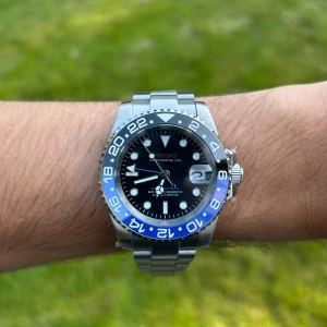 Seiko GMT Cosmic - Blue Automatic - Med en klassisk GMT-design är klockan utrustad med NH34-urverket, som ger möjligheten att visa tiden i flera tidszoner.   + Oyster Justerbar Länk  + GMT II-MASTER Eftermarknadstavla  + Transparent Bakstycke  + Seiko NH34 Automatisk Urverk  + Kommer i en klocklåda