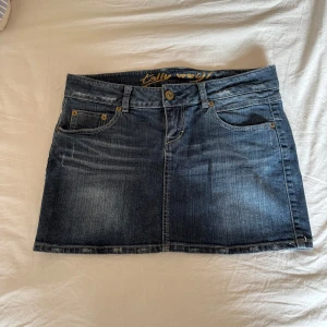 Mörkblå jeanskjol från Tally Weijl - Midjemått 40cm Längd 32cm Gren 12cm Säljer en klassisk mörkblå jeanskjol från Tally Weijl med fem fickor och knapp- samt dragkedjestängning. Kjolen har en rak passform och tydliga jeanssömmar. Perfekt till sneakers eller boots.