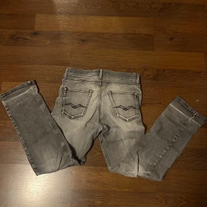 Replay grå jeans Thad slim fit - Snygga grå jeans från Replay, modell Thad. Jeansen har en slim passform, klassisk femficksdesign och slitna detaljer framtill för en cool look. Materialet är mjukt och stretchigt jeans, perfekt för dig som gillar en modern look. STORLEK 170 MEN SITTER SOM 30L 29W