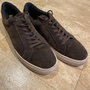 Bruna mockasneakers från Vagabond - Snygga bruna sneakers i mocka från Vagabond, storlek 46. De har en klassisk design med snörning och en benvit sula som ger en stilren look. Perfekta för en avslappnad stil. Använda en del men väl omhändertagna!