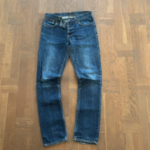 Nudie Jeans - Säljer ett par mörkblåa Nudie Jeans i modellen "Grim Tim", storlek W32 L34. Tillverkade i 100% bomull med en rak passform, vilket ger en stilren och bekväm look. Jeansen är i ett bra skick och är i väldig bra kvalitiet. Nypris 1600 kr. Priset går att diskutera.