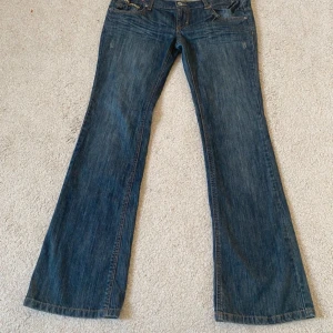 Bootcut jeans med broderade detaljer - Snygga blå bootcut jeans från Clockhouse med unika broderade detaljer i gult och rosa på fickorna. Mått: midja- 43cm, innebendlängd- 83cm, gylf-19cm. I perfekt skick!💗Lånade bilder!