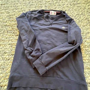 Mörkblå långärmad tröja från Moncler - Säljer en stilren svart långärmad tröja från Moncler. Tröjan har en rund halsringning och ett diskret Moncler-märke på bröstet. Perfekt för en avslappnad och trendig look.