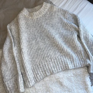 Grå stickad tröja - Mysig grå stickad tröja med ribbad struktur och långa ärmar. Perfekt för kyliga dagar och ger en avslappnad look. Passar bra till jeans eller leggings. Köpt på Ginatricot, str S. Använd en gång.