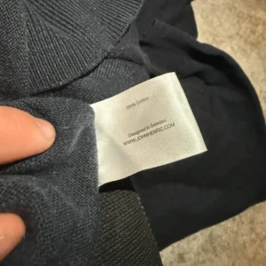 Mörkblå bomullströja från John Henric - Säljer en stilren mörkblå tröja från John Henric i 100% bomull. Tröjan har en dragkedja vid halsen och ribbade muddar vid ärmslut och nederkant. Perfekt för en avslappnad men snygg look.