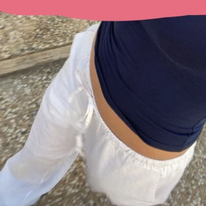 Vita linnebyxor - Säljer ett par vita linnebyxor med avslappnad passform och snörning i midjan. Perfekta för varma dagar med sitt lätta och luftiga material. Byxorna har en loose fit och är tillverkade i linne vilket ger en skön känsla mot huden. Finns en liten fläck vid hälen som syns på bild två men tycker inte man märker det när man har dem på sig!