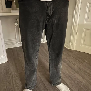 Svarta jeansbyxor från Woodbird - Snygga svarta jeansbyxor från Woodbird med en klassisk femficksdesign. Byxorna har en rak passform och stängs med dragkedja och knapp. Perfekta för en stilren look.