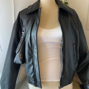 Svart skinnjacka från Reserved - Snygg svart skinnjacka från Reserved med dragkedja framtill. Jackan har en klassisk krage och elastisk nederkant för en bekväm passform. Perfekt för en stilren look.