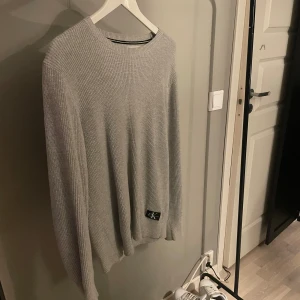Grå stickad tröja från Calvin Klein - Säljer denna stilrena stickade tröja från Calvin Klein i ett mycket bra skick.