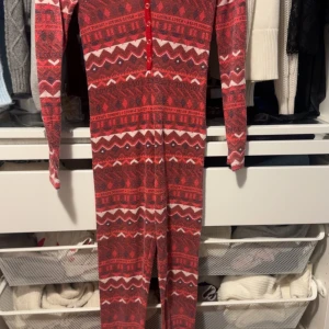 Röd och vit mönstrad jumpsuit från Hunkemöller - Säljer en mysig röd och vit mönstrad jumpsuit från Hunkemöller. Den har långa ärmar och knappar framtill. Nypris 499
