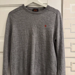 Grå merinoulltröja från Morris - Säljer en stilren grå tröja från Morris i 100% merinoull. Skick : 9/10. Storlek S men passar XS. Tröjan har en liten röd broderad detalj på bröstet och rund halsringning. Perfekt för kyligare dagar. Skriv gärna om du har frågor eller funderingar. 
