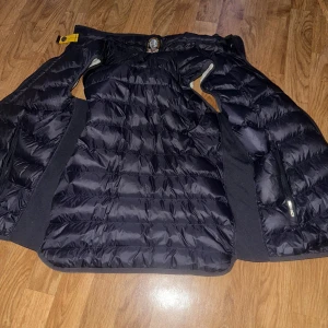 Svart väst från Parajumpers - Säljer en svart väst från Parajumpers med quiltad design. Jackan har dragkedjor på sidorna och en gul detalj vid kragen. Insidan är ljus och kontrasterar snyggt mot den mörka utsidan. Varan är i väldigt bra skick då den är köpt för 1 vecka sen och då haft på mig den 1 gång. Västen är perfekt för våren dessutom!