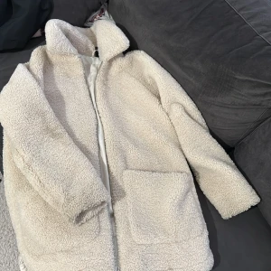 Beige teddyjacka - Mysig beige teddyjacka med långa ärmar och dragkedja. Perfekt för kyliga dagar när du vill hålla dig varm och stilren. Jackan har en klassisk krage och stora fickor framtill. Storlek XS men passar även som S