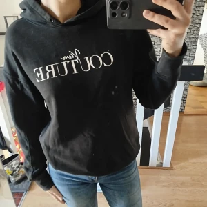 Svart hoodie  - Säljer en svart hoodie med vit text på framsidan. Tröjan har en klassisk design med huva och långa ärmar. Perfekt för en avslappnad stil.