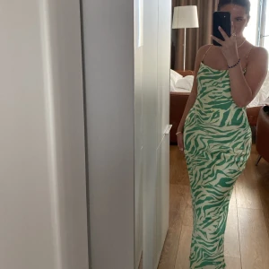 Satin lång klänning  - Lång satin klänning med gröna mönster. Sitter så fint och man kan justera hur tajt man vill ha den💚