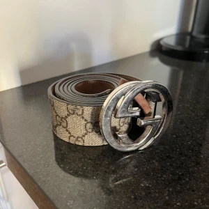 Beige bälte med silverfärgat spänne - Beige bälte från Gucci med mönster. Storlek 105 42.