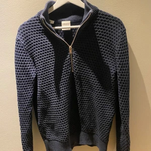 Mörkblå stickad tröja från Selected Homme - Säljer en snygg mörkblå stickad tröja från Selected Homme. Tröjan har en dragkedja framtill och en ribbad krage. Perfekt för kyligare dagar med sin stilrena design och bekväma passform.